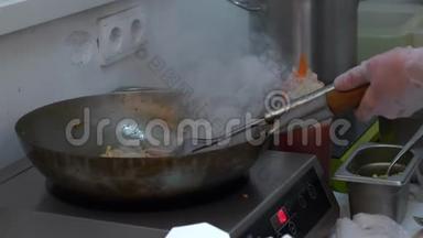 厨师在<strong>炒锅</strong>上做亚洲面条，加入酱汁，在电炉上用烟搅拌